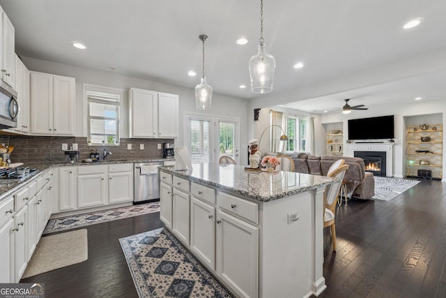 3755 Gardenside Ct, Alpharetta, GA 30004 - kitchen with stainless steel appliances, ceiling fan, a center island, a glass covered fireplace, and white cabinetry