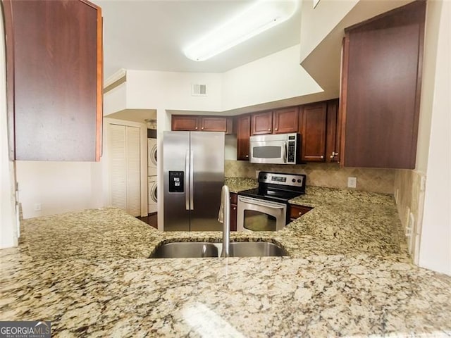 200 Renaissance Pkwy NE Unit 310, Atlanta, GA 30308 - kitchen featuring stainless steel appliances, stacked washer and clothes dryer, light stone counters, and decorative backsplash