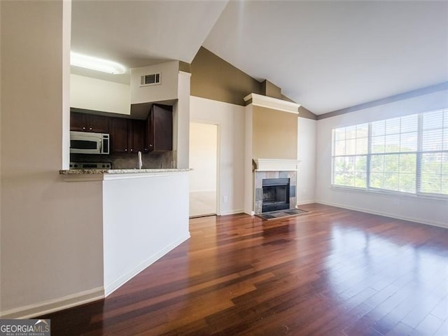 200 Renaissance Pkwy NE Unit 310, Atlanta, GA 30308 - unfurnished living room with vaulted ceiling, wood finished floors, and a tiled fireplace