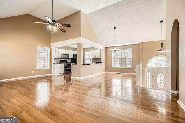 13 Cliff Ct, Villa Rica, GA 30180 - unfurnished living room featuring high vaulted ceiling, ceiling fan, arched walkways, light wood-style flooring, and a chandelier