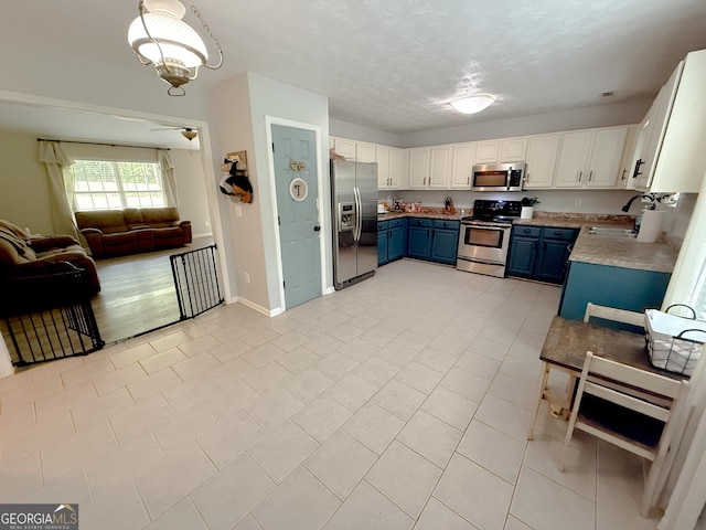653 Al Roberts Rd, Senoia, GA 30276 - kitchen featuring stainless steel appliances, blue cabinetry, a sink, open floor plan, and light countertops