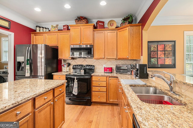 4445 Vanadium Bnd, Cumming, GA 30040 - kitchen featuring appliances with stainless steel finishes, a sink, crown molding, light wood-style floors, and light stone counters
