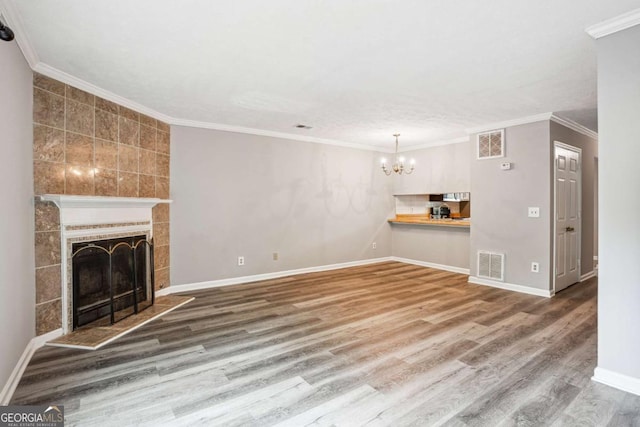 2049 Charter Ln, Lithonia, GA 30058 - unfurnished living room with a chandelier, wood finished floors, baseboards, a tile fireplace, and ornamental molding
