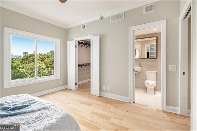 587 Virginia Ave NE Apt 609, Atlanta, GA 30306 - bedroom featuring crown molding, wood finished floors, baseboards, ensuite bath, and a closet