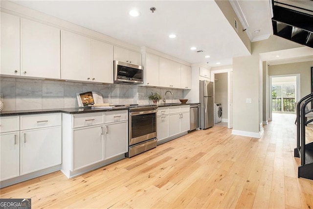 587 Virginia Ave NE Apt 609, Atlanta, GA 30306 - kitchen featuring appliances with stainless steel finishes, washer / dryer, a sink, crown molding, and dark countertops