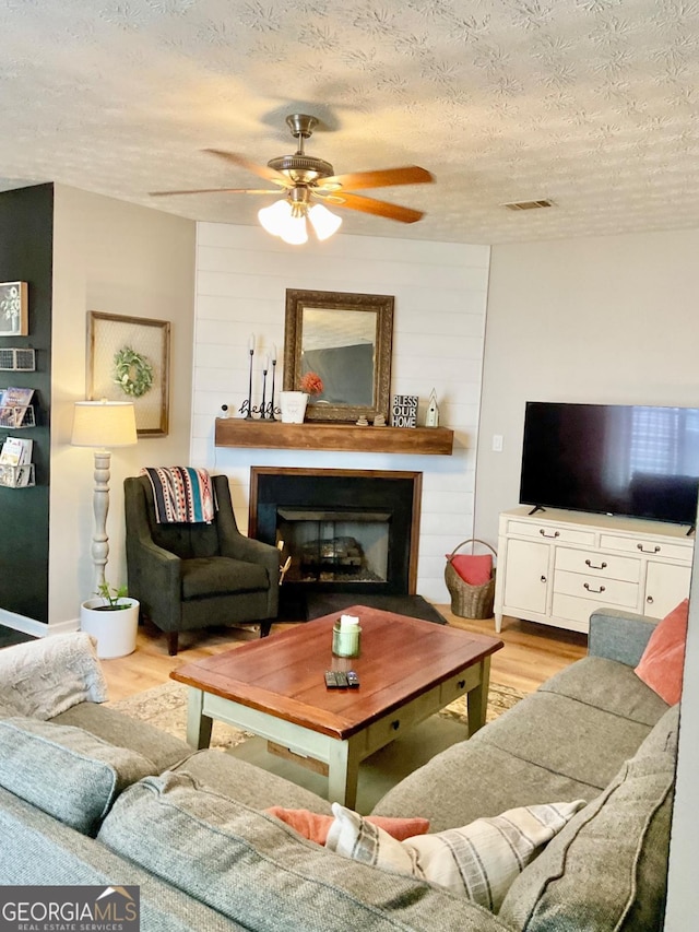 4863 Beacon Ridge Ln, Flowery Branch, GA 30542 - living room with wood finished floors, a textured ceiling, a ceiling fan, and a fireplace