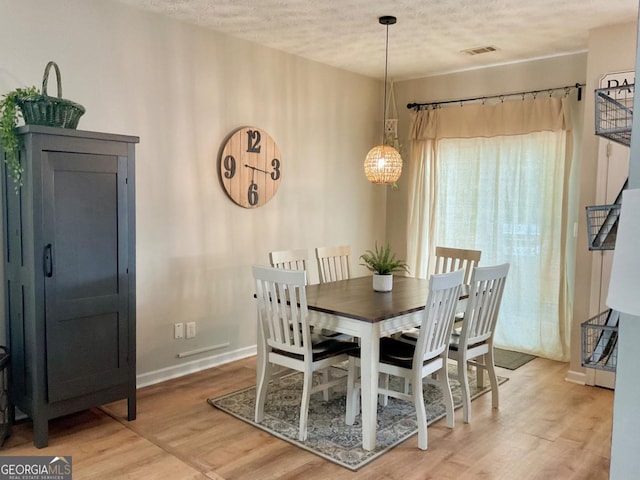 4863 Beacon Ridge Ln, Flowery Branch, GA 30542 - dining space featuring a textured ceiling, light wood finished floors, baseboards, and a chandelier