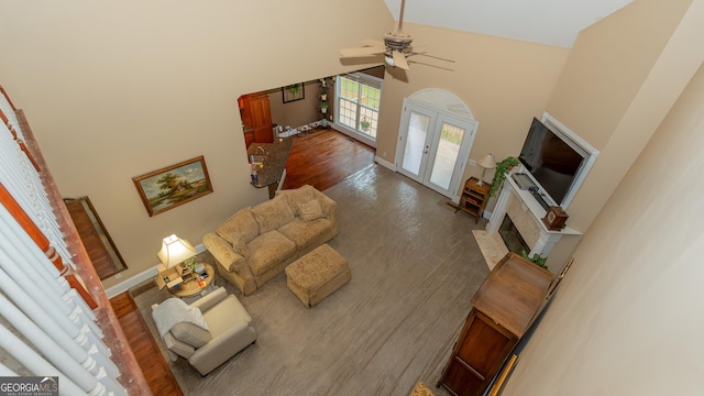 219 Periwinkle Way, Pendergrass, GA 30567 - living room featuring a high ceiling, a ceiling fan, wood finished floors, a fireplace with flush hearth, and baseboards