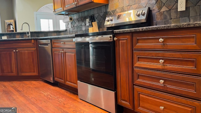 219 Periwinkle Way, Pendergrass, GA 30567 - kitchen featuring stainless steel appliances, decorative backsplash, light wood-style flooring, and dark stone counters