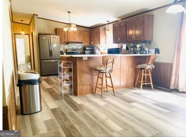 1909 Scotland Rd, Dublin, GA 31021 - kitchen with freestanding refrigerator, a peninsula, light wood finished floors, a breakfast bar area, and light countertops