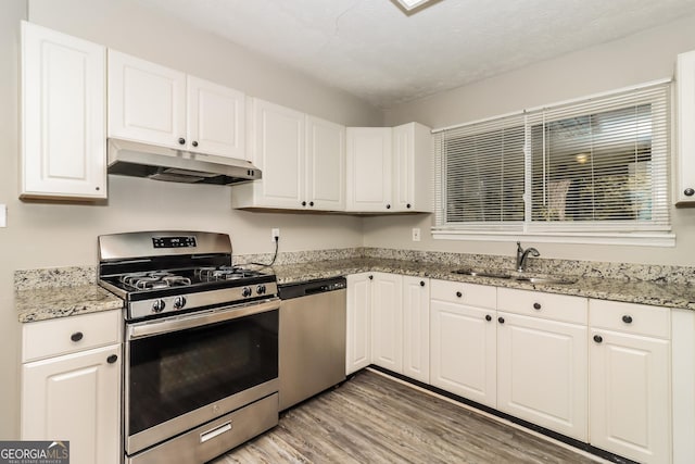 2624 Windridge Dr, Acworth, GA 30102 - kitchen featuring appliances with stainless steel finishes, under cabinet range hood, light wood-type flooring, and white cabinetry