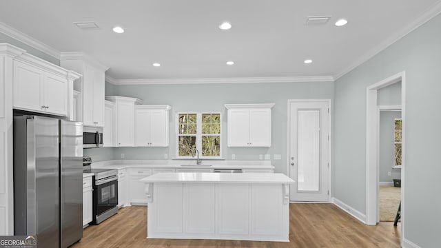 5016 Smith Rd SE, Townsend, GA 31331 - kitchen featuring appliances with stainless steel finishes, light countertops, a sink, white cabinetry, and crown molding