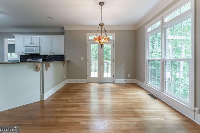 3801 Stonebriar Ln, Duluth, GA 30097 - kitchen featuring white microwave, light wood finished floors, ornamental molding, dark stone counters, and decorative light fixtures