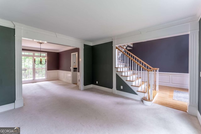 3801 Stonebriar Ln, Duluth, GA 30097 - unfurnished living room featuring a chandelier, crown molding, stairs, carpet floors, and wainscoting