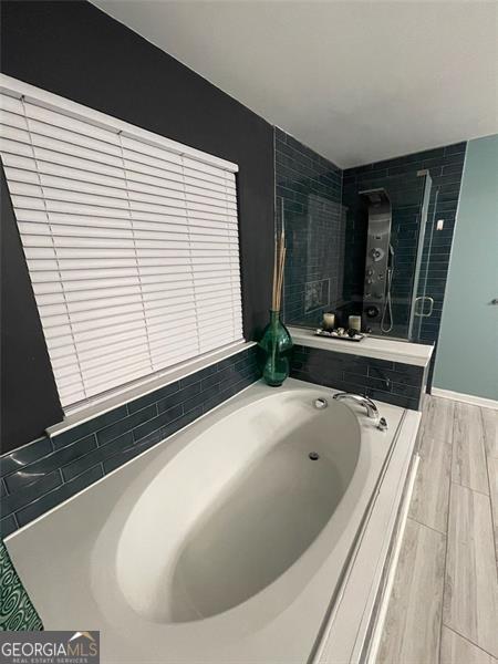 2030 Hydrangea Ln, Austell, GA 30106 - bathroom featuring a garden tub, a stall shower, and wood finished floors