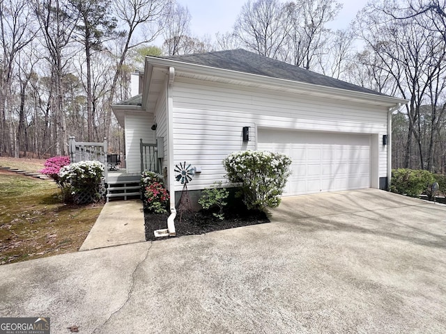 212 Teepee Trl, Whitesburg, GA 30185 - view of property exterior with concrete driveway, an attached garage, a wooden deck, roof with shingles, and a chimney