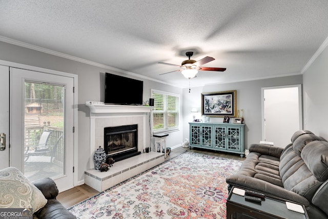 212 Teepee Trl, Whitesburg, GA 30185 - living area with a textured ceiling, wood finished floors, ceiling fan, crown molding, and a tiled fireplace