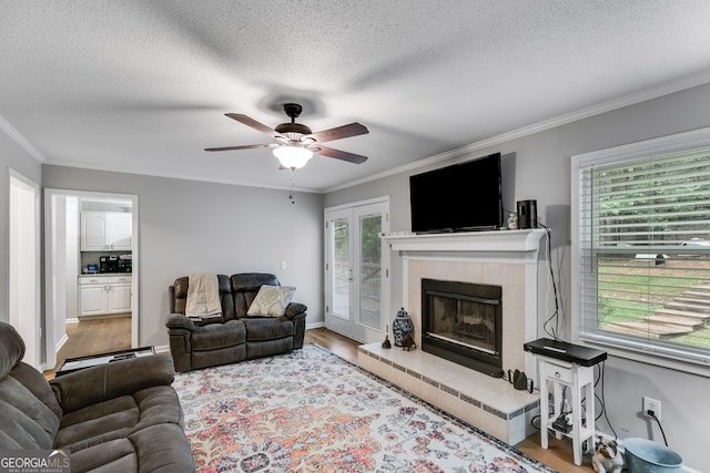 212 Teepee Trl, Whitesburg, GA 30185 - living area featuring a ceiling fan, ornamental molding, a tiled fireplace, wood finished floors, and a textured ceiling