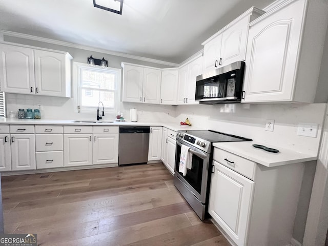 212 Teepee Trl, Whitesburg, GA 30185 - kitchen featuring appliances with stainless steel finishes, light wood-type flooring, crown molding, white cabinetry, and light countertops
