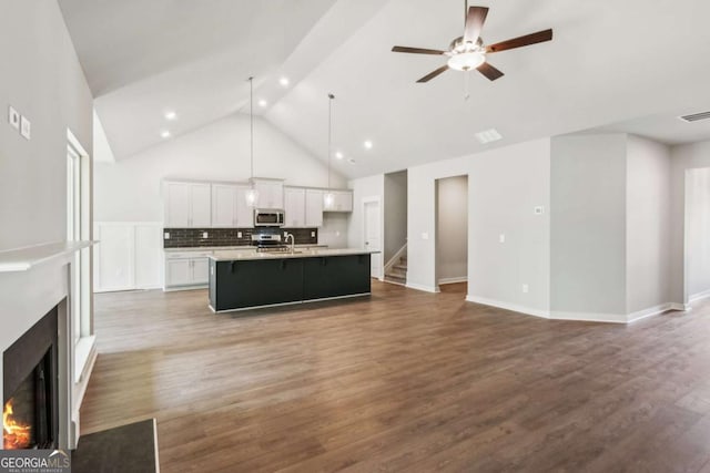 4300 Links Blvd, Jefferson, GA 30549 - unfurnished living room with a lit fireplace, high vaulted ceiling, a sink, a ceiling fan, and wood finished floors