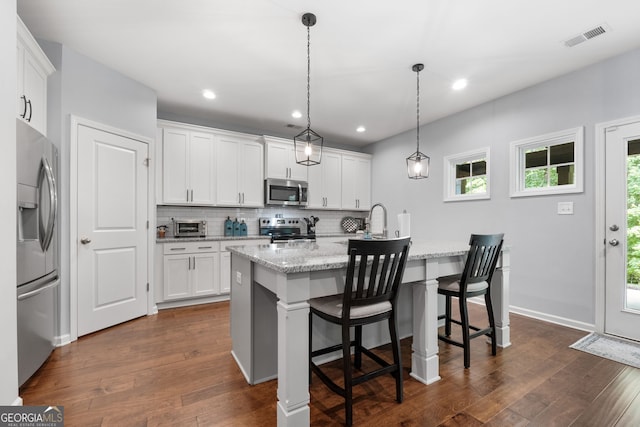 8 Saint Charles Ave, Sharpsburg, GA 30277 - kitchen with stainless steel appliances, dark wood-style floors, a center island with sink, decorative backsplash, and white cabinetry