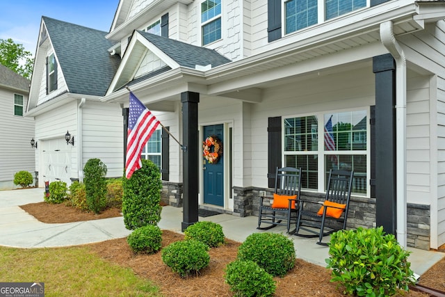 8 Saint Charles Ave, Sharpsburg, GA 30277 - property entrance featuring covered porch, an attached garage, stone siding, and roof with shingles