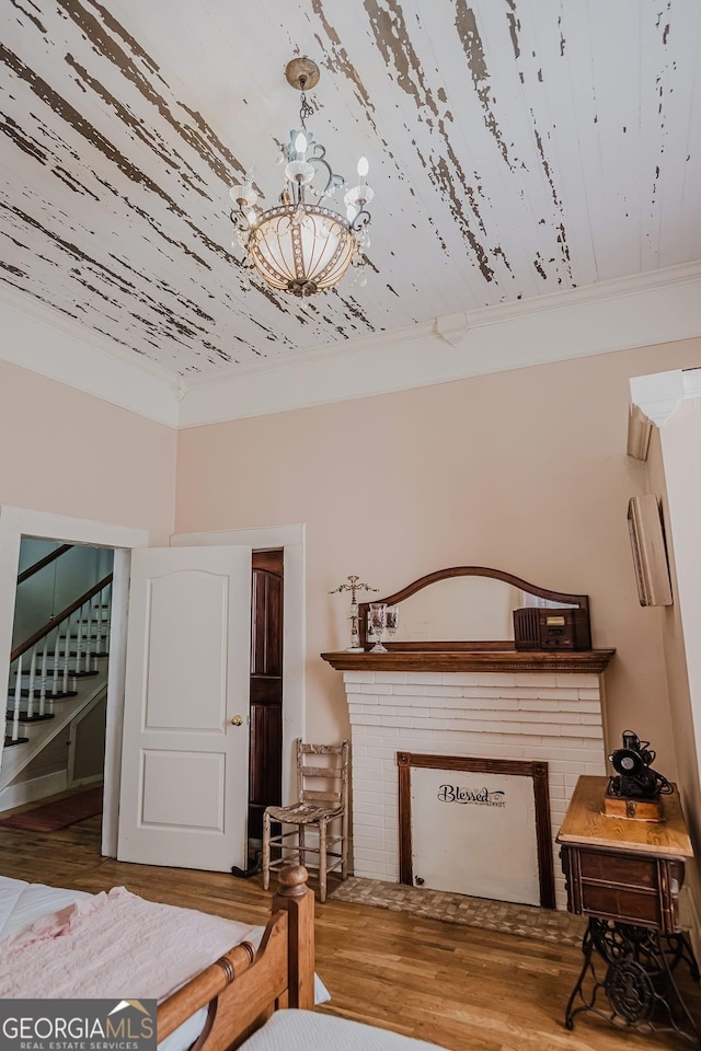 428 Elm St, Barnesville, GA 30204 - bedroom featuring wood finished floors, a chandelier, a fireplace, and crown molding