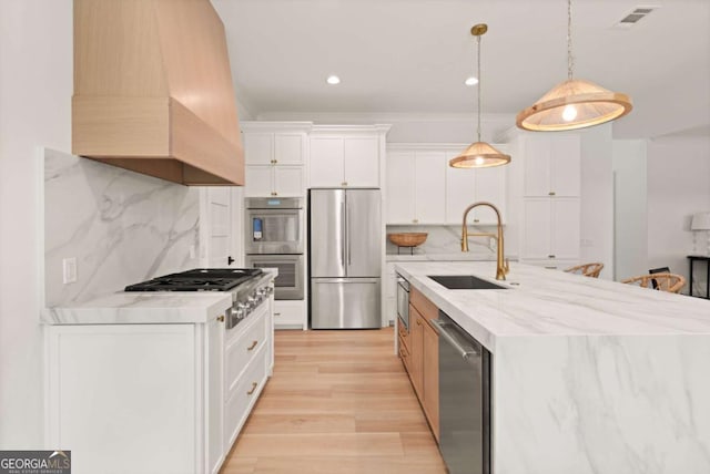 616 Neptune Way, Saint Simons, GA 31522 - kitchen with appliances with stainless steel finishes, light wood-type flooring, backsplash, white cabinets, and custom exhaust hood