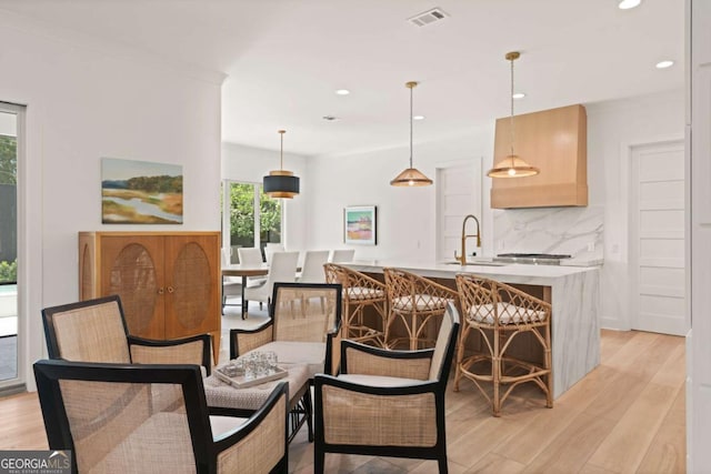 616 Neptune Way, Saint Simons, GA 31522 - kitchen with tasteful backsplash, light wood-style flooring, recessed lighting, a kitchen island with sink, and light countertops