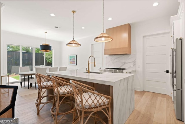 616 Neptune Way, Saint Simons, GA 31522 - kitchen with tasteful backsplash, recessed lighting, light wood-style floors, a kitchen island with sink, and custom exhaust hood