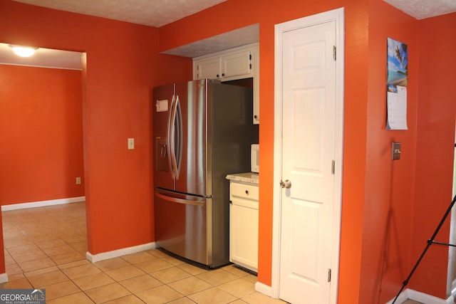 3255 Hunters Crossing Pt, Lithonia, GA 30038 - kitchen with stainless steel fridge with ice dispenser, baseboards, white cabinetry, and light tile patterned flooring