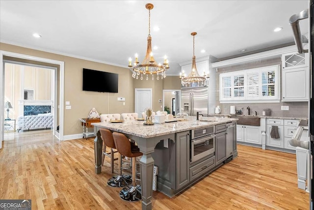 4670 Hamden Forest Dr SW, Atlanta, GA 30331 - kitchen featuring stainless steel built in fridge, a chandelier, crown molding, an island with sink, and light wood-style floors