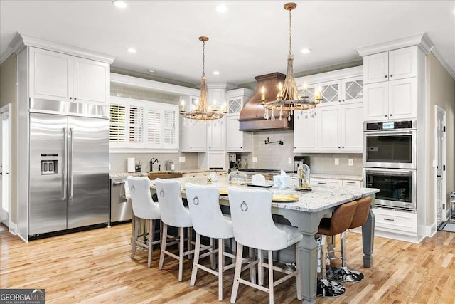 4670 Hamden Forest Dr SW, Atlanta, GA 30331 - kitchen with stainless steel appliances, a chandelier, custom exhaust hood, backsplash, and white cabinetry