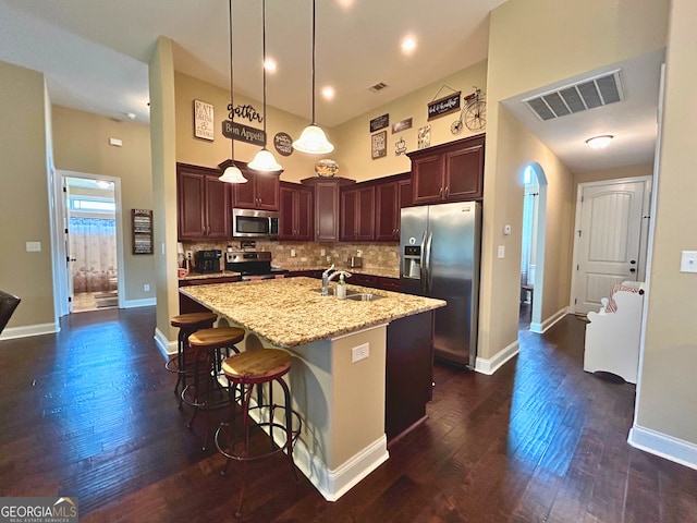 307 Legacy Park Dr, Perry, GA 31069 - kitchen with stainless steel appliances, dark wood finished floors, a center island with sink, pendant lighting, and light stone countertops