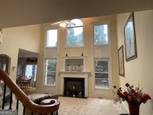 2123 Floral Ridge Dr, Dacula, GA 30019 - carpeted living room with a ceiling fan, a fireplace with flush hearth, a high ceiling, plenty of natural light, and arched walkways