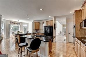 2123 Floral Ridge Dr, Dacula, GA 30019 - kitchen featuring black fridge, dark countertops, a center island, light wood finished floors, and a kitchen breakfast bar