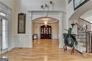 2123 Floral Ridge Dr, Dacula, GA 30019 - entrance foyer featuring arched walkways, a decorative wall, wood finished floors, stairs, and a wainscoted wall