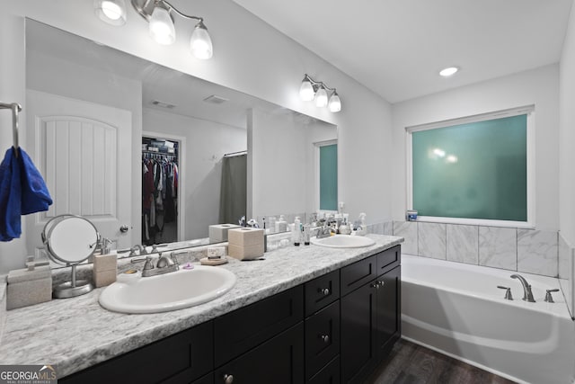 102 Brookstone Way, Rincon, GA 31326 - bathroom featuring double vanity, wood finished floors, a garden tub, and a spacious closet