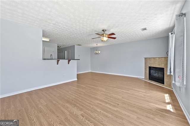 695 Georgetown Ct, Jonesboro, GA 30236 - unfurnished living room featuring a ceiling fan, a tile fireplace, light wood-style floors, a textured ceiling, and baseboards