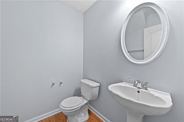 695 Georgetown Ct, Jonesboro, GA 30236 - half bathroom featuring wood finished floors, baseboards, toilet, and a sink