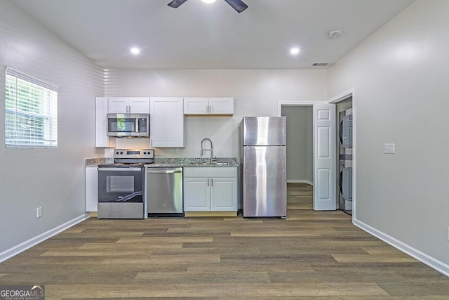 2065 Freeman St, Macon, GA 31201 - kitchen featuring appliances with stainless steel finishes, stacked washer and clothes dryer, a sink, white cabinets, and a ceiling fan