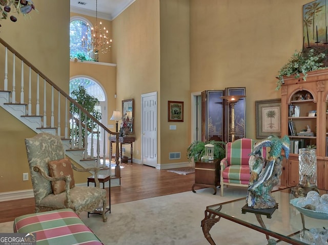 307 Worthing Ln, Mcdonough, GA 30253 - living area featuring a towering ceiling, stairway, crown molding, a chandelier, and wood finished floors