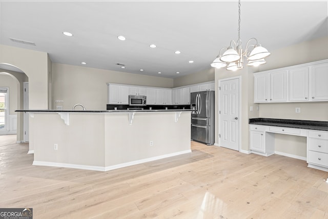 2030 Brook Meadow Dr, Alpharetta, GA 30005 - kitchen featuring stainless steel appliances, a kitchen bar, arched walkways, light wood-type flooring, and recessed lighting