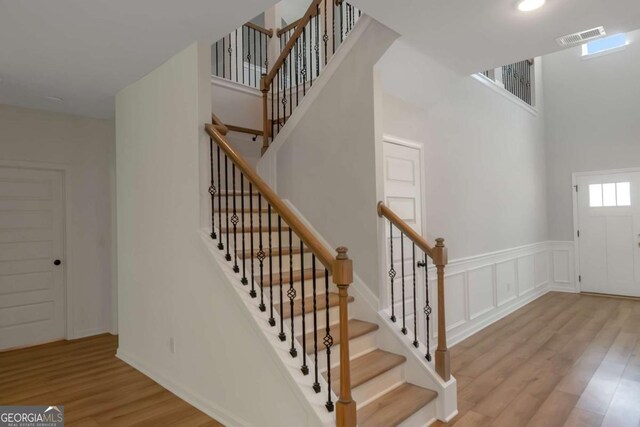 420 Tavistock Ct, Mcdonough, GA 30252 - stairway featuring wood finished floors, a high ceiling, a wainscoted wall, and a decorative wall