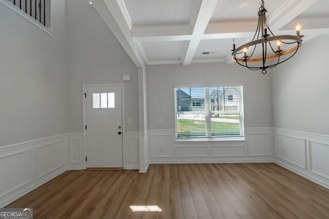 420 Tavistock Ct, Mcdonough, GA 30252 - foyer entrance with a chandelier, light wood-style floors, beam ceiling, coffered ceiling, and a wainscoted wall