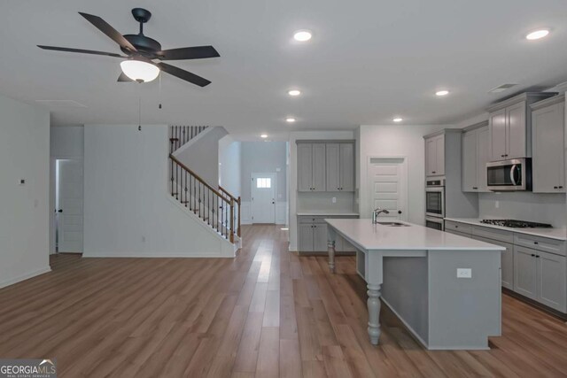 420 Tavistock Ct, Mcdonough, GA 30252 - kitchen with gray cabinets, appliances with stainless steel finishes, a sink, a kitchen island with sink, and light wood-style flooring