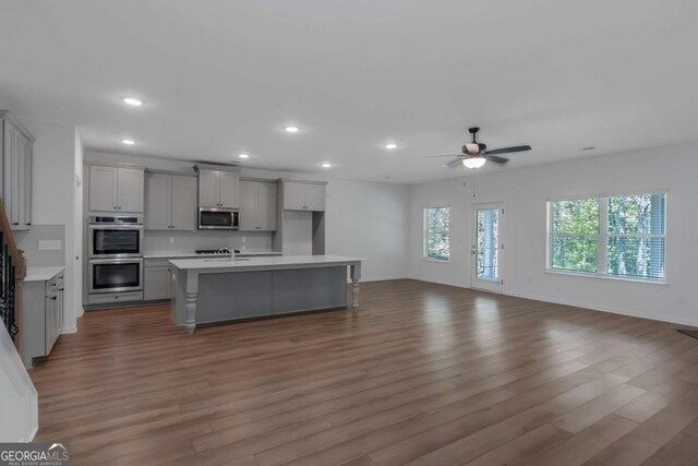 420 Tavistock Ct, Mcdonough, GA 30252 - kitchen with stainless steel appliances, gray cabinets, open floor plan, light countertops, and wood finished floors