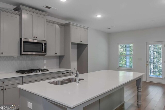 420 Tavistock Ct, Mcdonough, GA 30252 - kitchen featuring a sink, stainless steel microwave, gray cabinets, gas cooktop, and an island with sink