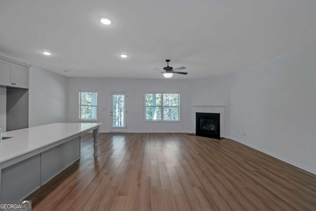 420 Tavistock Ct, Mcdonough, GA 30252 - unfurnished living room featuring a ceiling fan, recessed lighting, light wood-style flooring, baseboards, and a fireplace with flush hearth