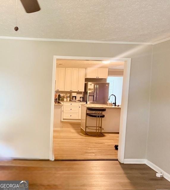 219 Broad St, Carrollton, GA 30117 - kitchen with stainless steel fridge, ornamental molding, a breakfast bar, a textured ceiling, and light wood-style floors